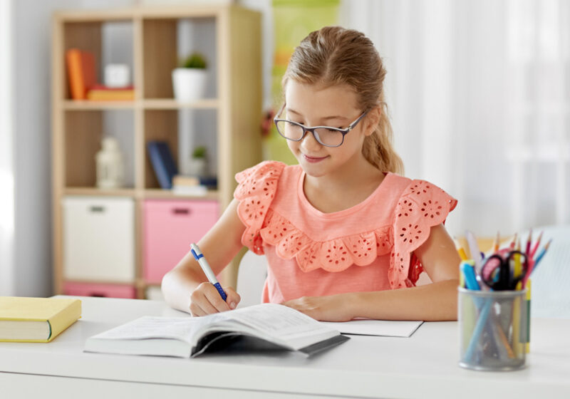 Zdolna dziewczynka w wieku szkolnym uczy się z zadowoleniem